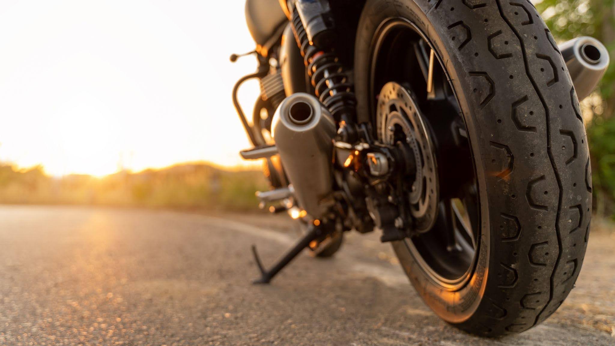 A motorcycle parked on the road silhouetted against a vibrant sunset sky