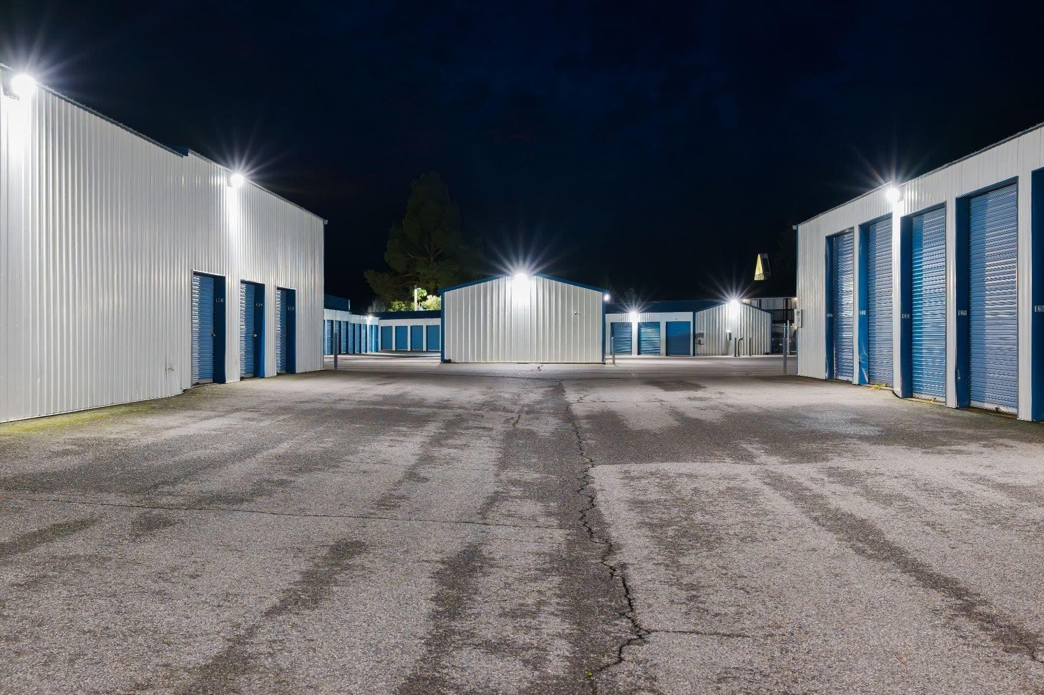 Nighttime view of a storage unit illuminated by lights highlighting its structure against the dark sky